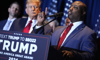 FILE - Republican presidential candidate former President Donald Trump listens as Sen. Tim Scott, R-S.C., speaks at a primary election night party at the South Carolina State Fairgrounds in Columbia, S.C., Saturday, Feb. 24, 2024. (AP Photo/Andrew Harnik, File)